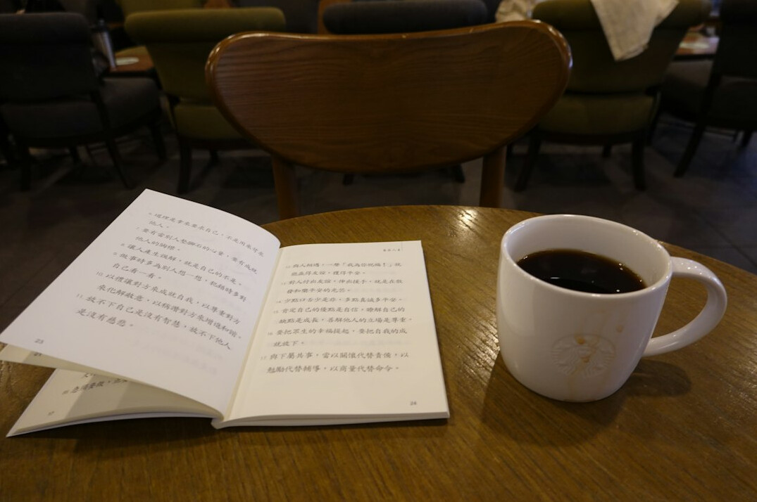 Open book next to a cup of coffee on a wooden table